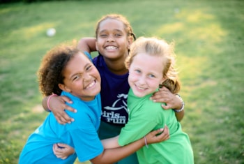 Girls on the Run participants smile in different color GOTR shirts